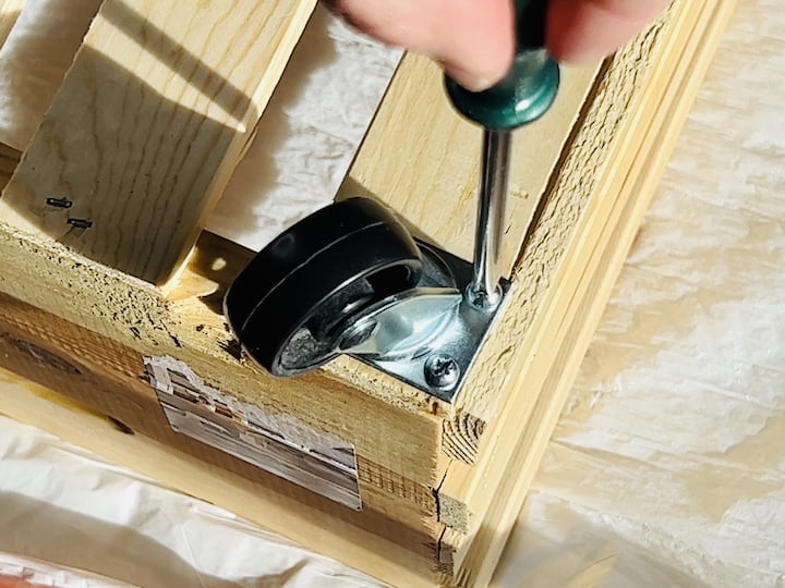 Step 4: Attach WheelsFlip the crate upside down and attach one wheel to each corner. Consider making pilot holes with a drill for easier screwing. Repeat the process for all four corners.