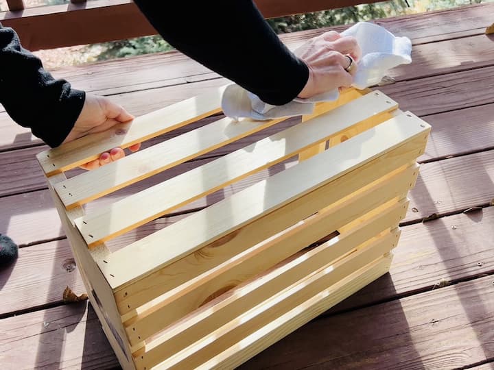 Begin by sanding the entire exterior and interior of the crate to remove slivers and splinters. Wipe it down with a damp cloth to eliminate sawdust, ensuring a smooth surface for the next steps.