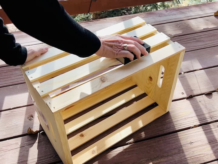 I decided to lightly sand the crate since we'd be storing blankets in them and our hands would be reaching in and out of them.  You can use an orbital sander or a sanding block, whichever you prefer.