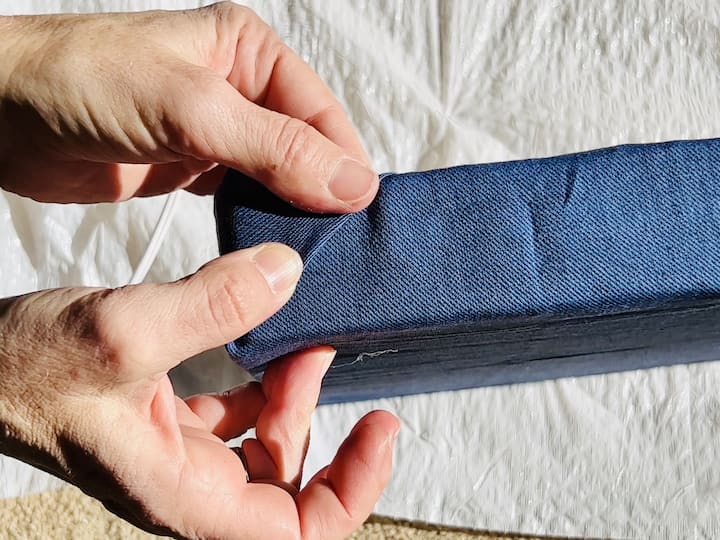 Finishing Touches: Fold the fabric neatly at the corners, adding a bit of glue to secure them in place. This step is similar to wrapping a present. Continue until all sides are covered and the fabric is securely attached to the lid.