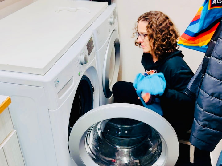 Chas placing clothes in washing machine