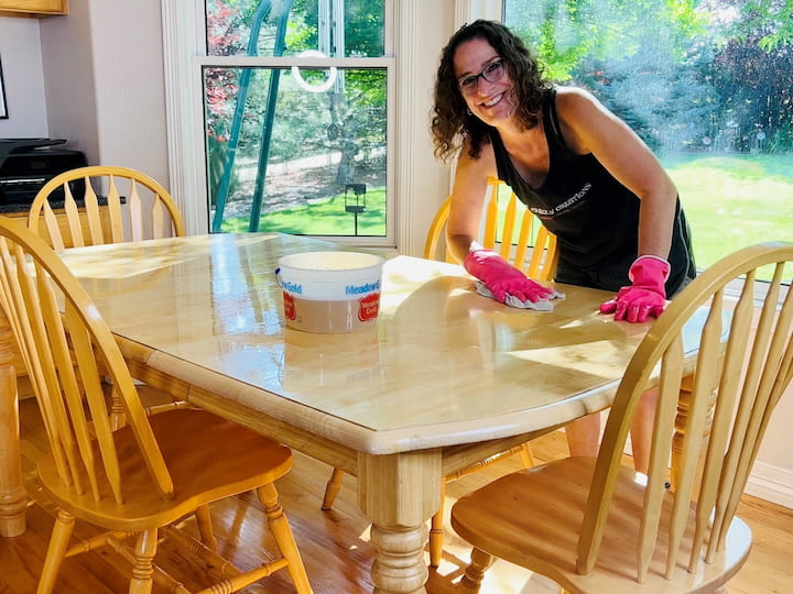 Mix 1/4 cup of Murphy's Oil Soap with a gallon of water. Use a clean washcloth to wipe down wood surfaces, starting with tables and then cabinets. Wipe cabinets from top to bottom, focusing on crevices and areas touched by hands.