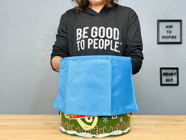 Choose any bucket you like; I opted for an old popcorn bucket. Wrap the apron around it and tie it in the back. Alternatively, you can glue it for added sturdiness. Now, let's bring it all together. 