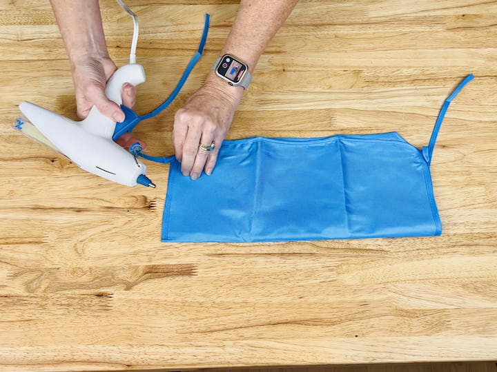 Here's a handy hack for you. Head over to Dollar Tree and snag one of their aprons. Begin by cutting off the neckties, then fold the top part underneath and the bottom part up. Take out your trusty hot glue gun and secure the sides and sections to craft pockets with this apron.