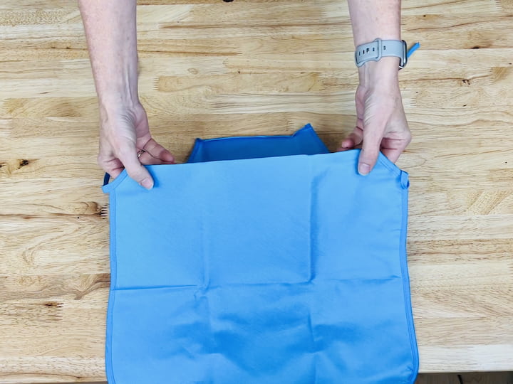 Here's a handy hack for you. Head over to Dollar Tree and snag one of their aprons. Begin by cutting off the neckties, then fold the top part underneath and the bottom part up. Take out your trusty hot glue gun and secure the sides and sections to craft pockets with this apron.