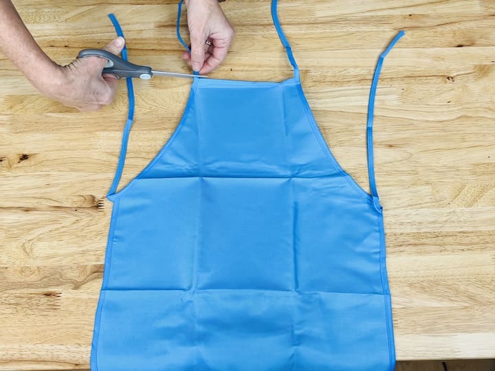 Here's a handy hack for you. Head over to Dollar Tree and snag one of their aprons. Begin by cutting off the neckties, then fold the top part underneath and the bottom part up. Take out your trusty hot glue gun and secure the sides and sections to craft pockets with this apron.