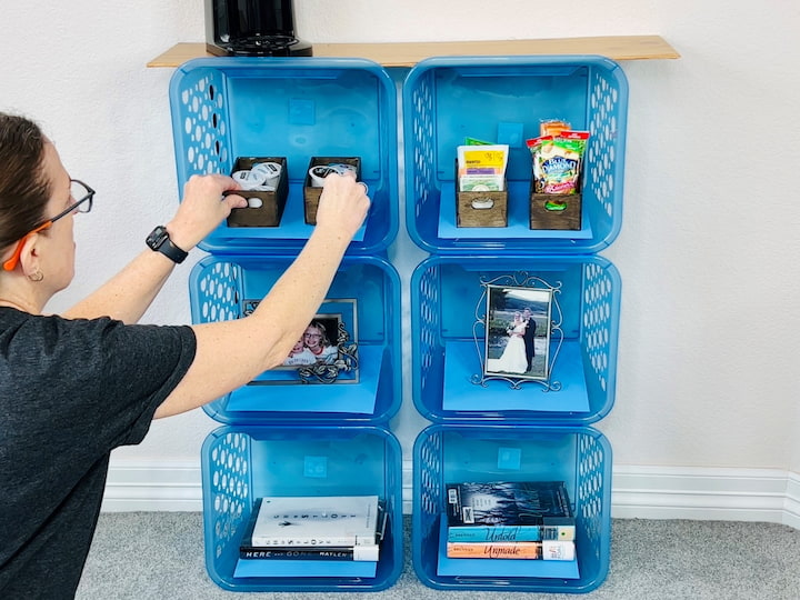 Now it's time to decorate. If you want to use these for closed storage you can buy some bins, baskets, or soft cloth crates to slide in to create drawers. I started by adding some books and frames on the bottom. I also added some snacks and coffee pods with a small coffee pot on top. I also added some hand sanitizer and a cute little hot chocolate. sign. You could also add a glass vase or flower pot.