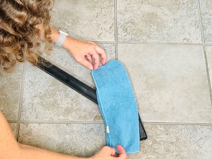 2. Wet a microfiber cloth and wring it out well. Attach it to the bottom of your steam mop using clips.