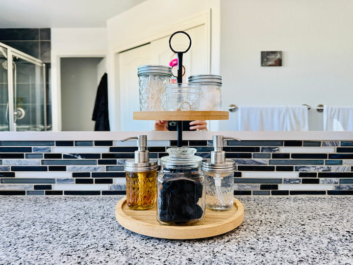 glass jars used for bathroom storage on a tierd tray