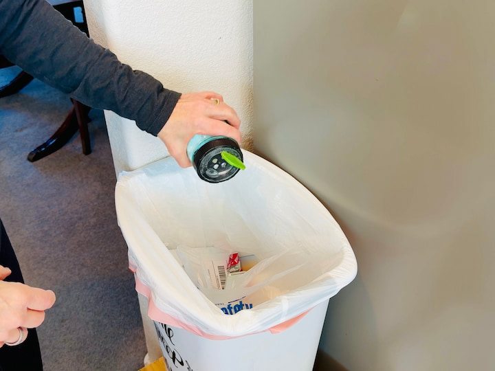 sprinkling baking soda into a trash can