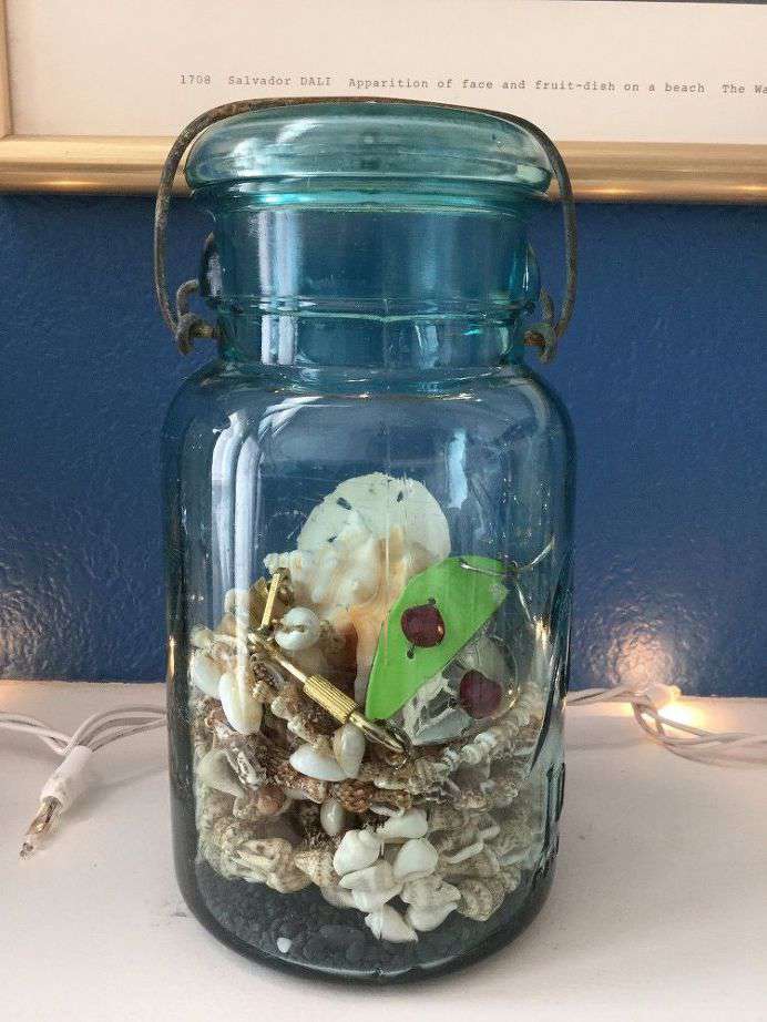 glass jar holding sand and shells